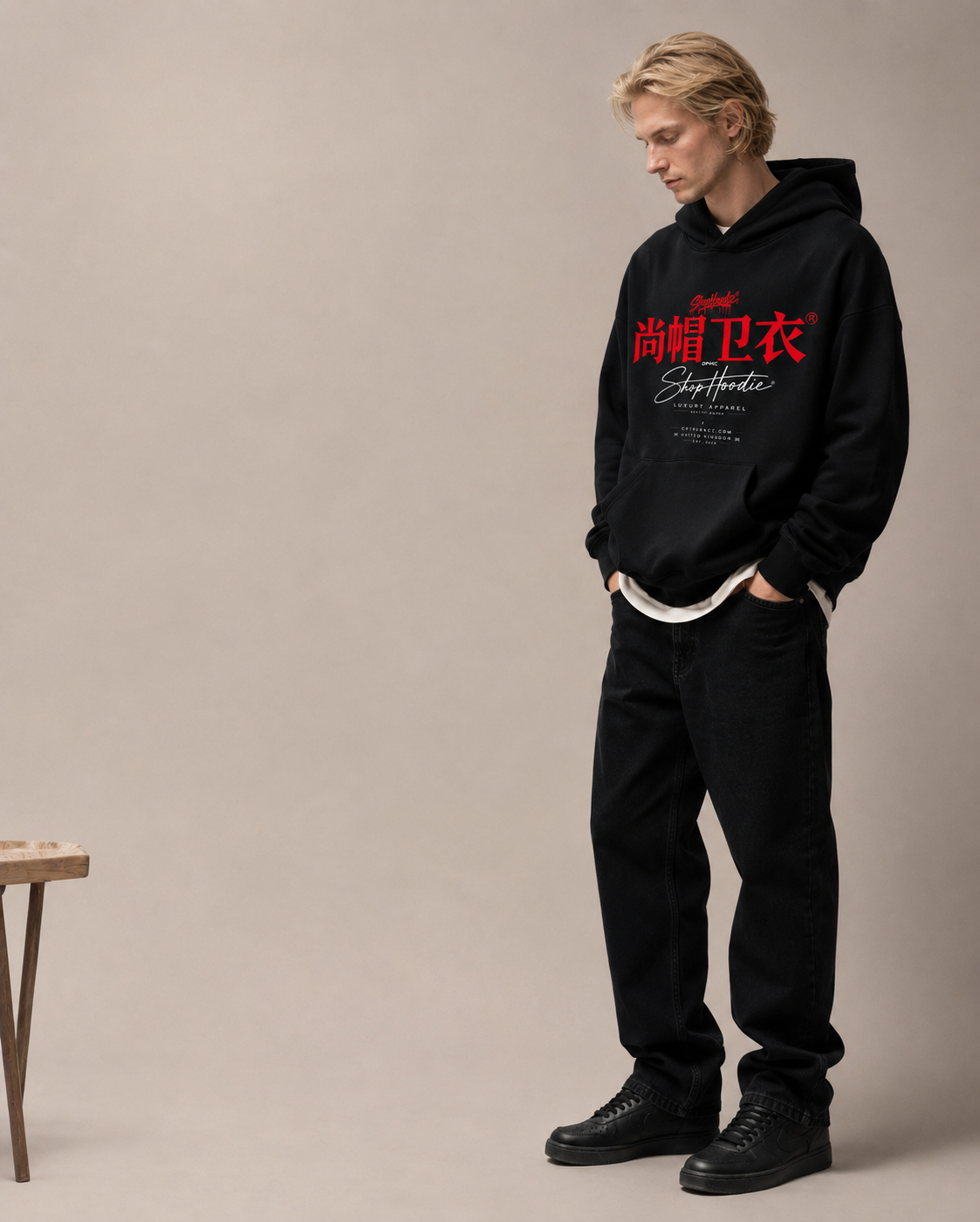 Person wearing a black shophoodie brand hoodie with red text on a beige background