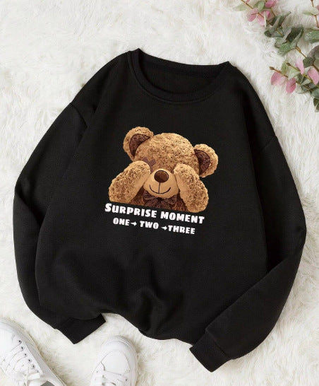Black sweatshirt with a teddy bear graphic and text on a white surface.