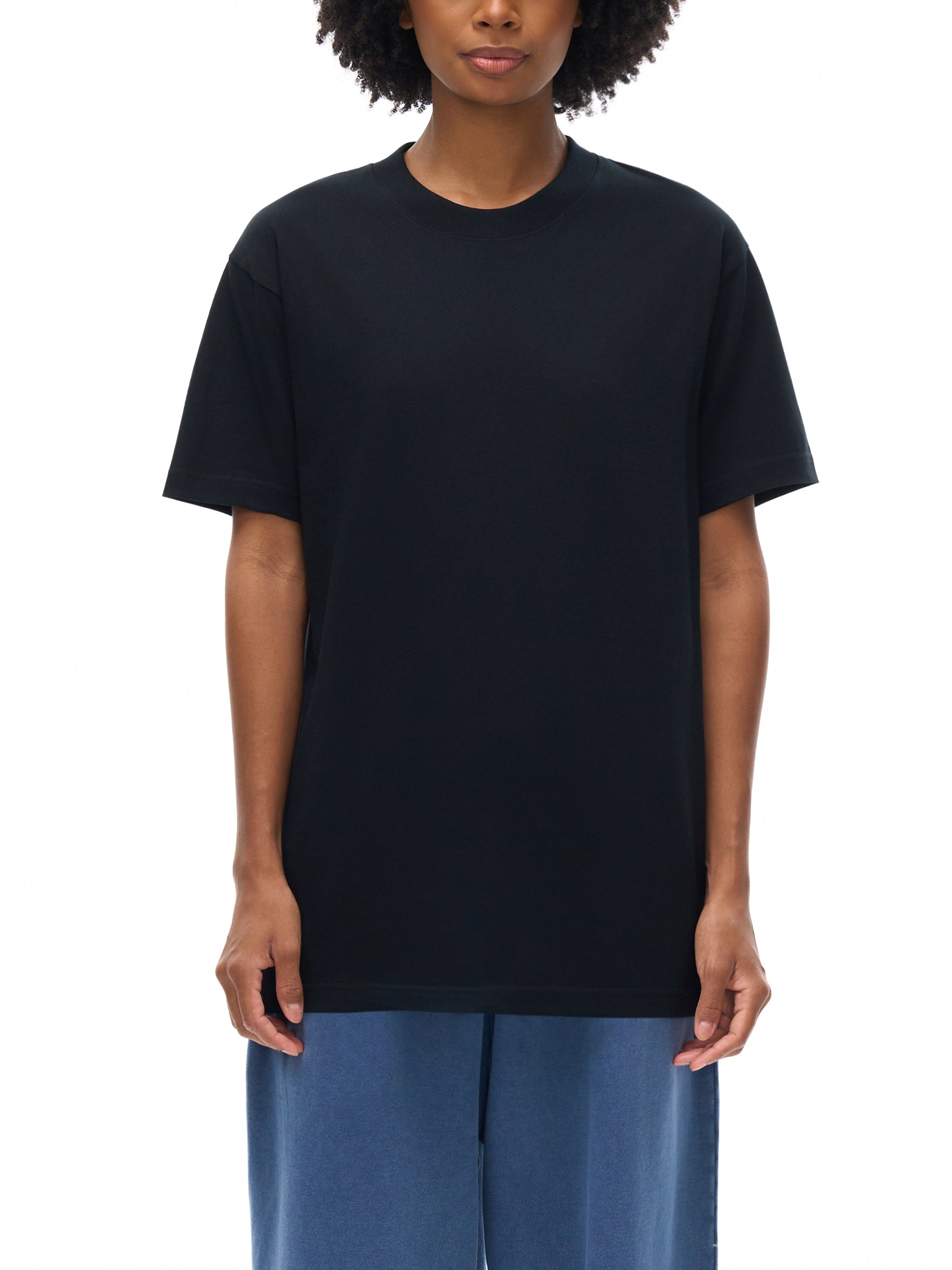 Person wearing a black t-shirt and blue pants on a white background