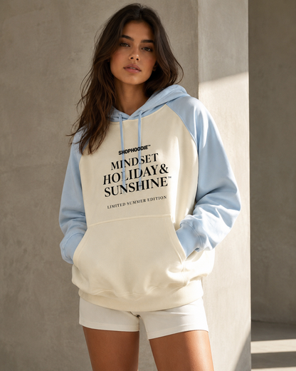 Woman wearing a hoodie with text standing against a neutral wall