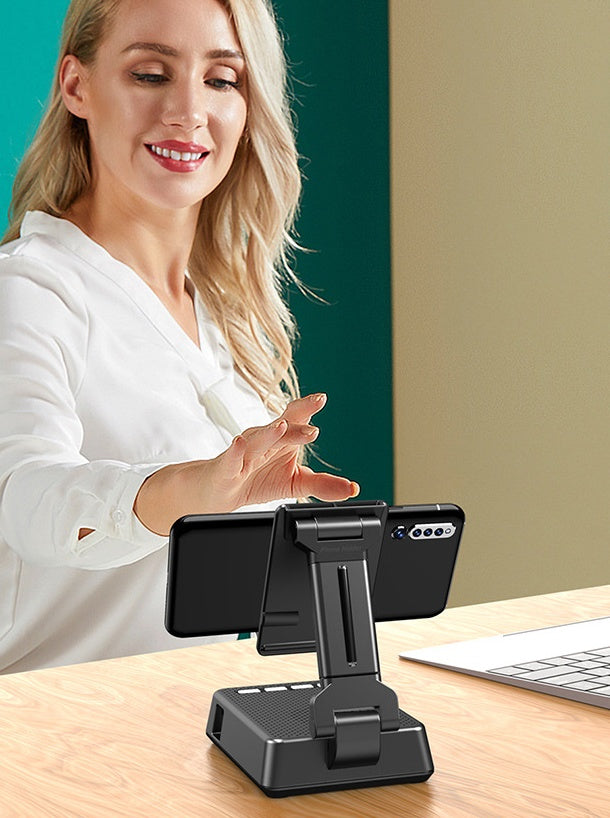 Woman using a phone holder at a desk with a keyboard and computer monitor in the background.