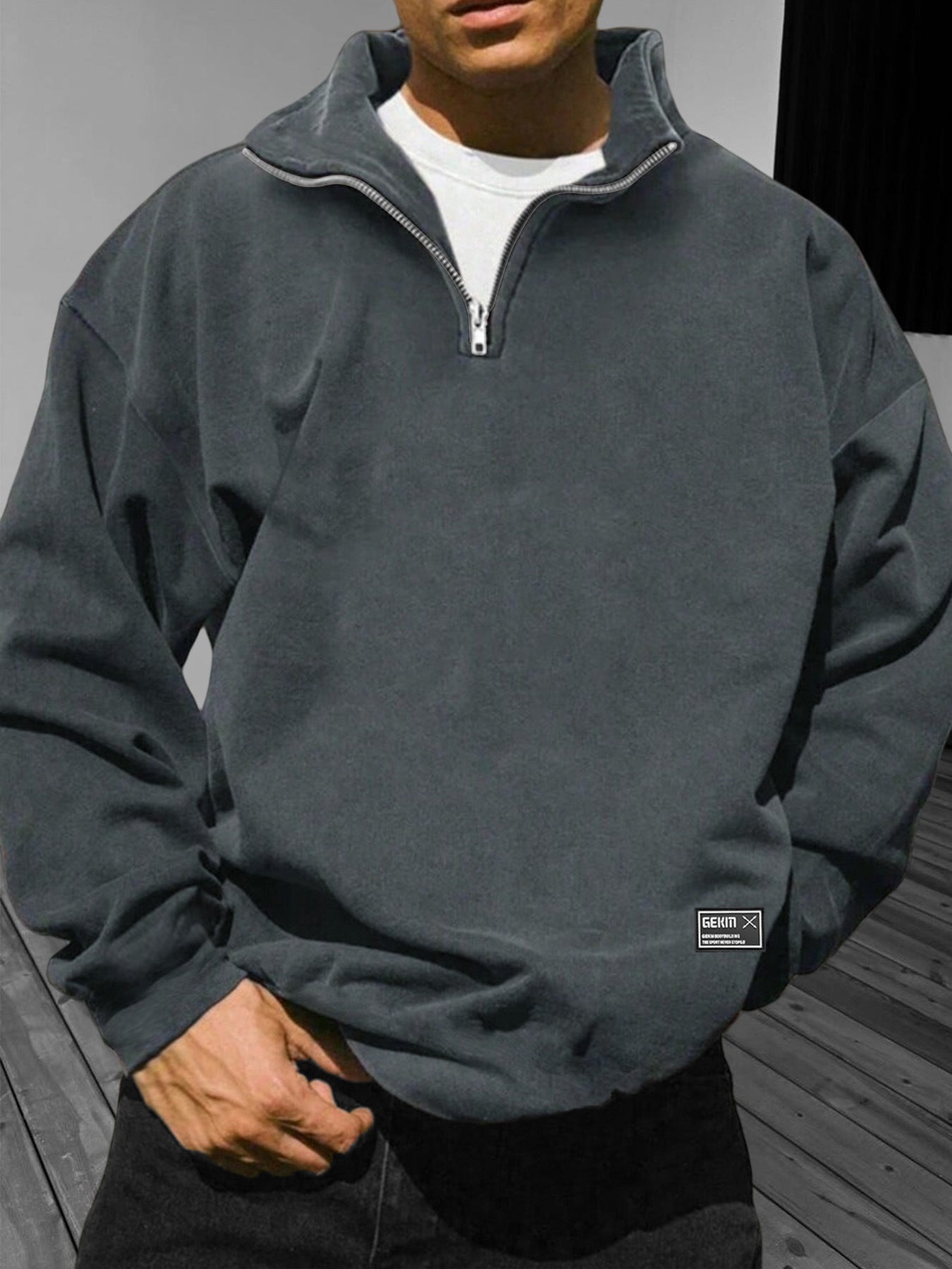 Person wearing a gray pullover with a visible brand logo on a neutral background