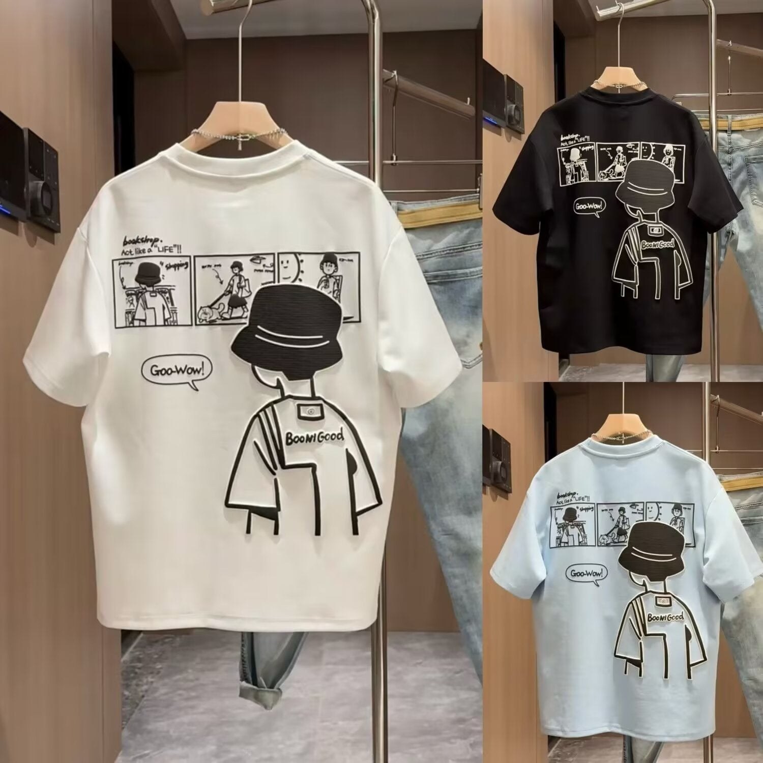 Three t-shirts with cartoon designs on hangers against a neutral background
