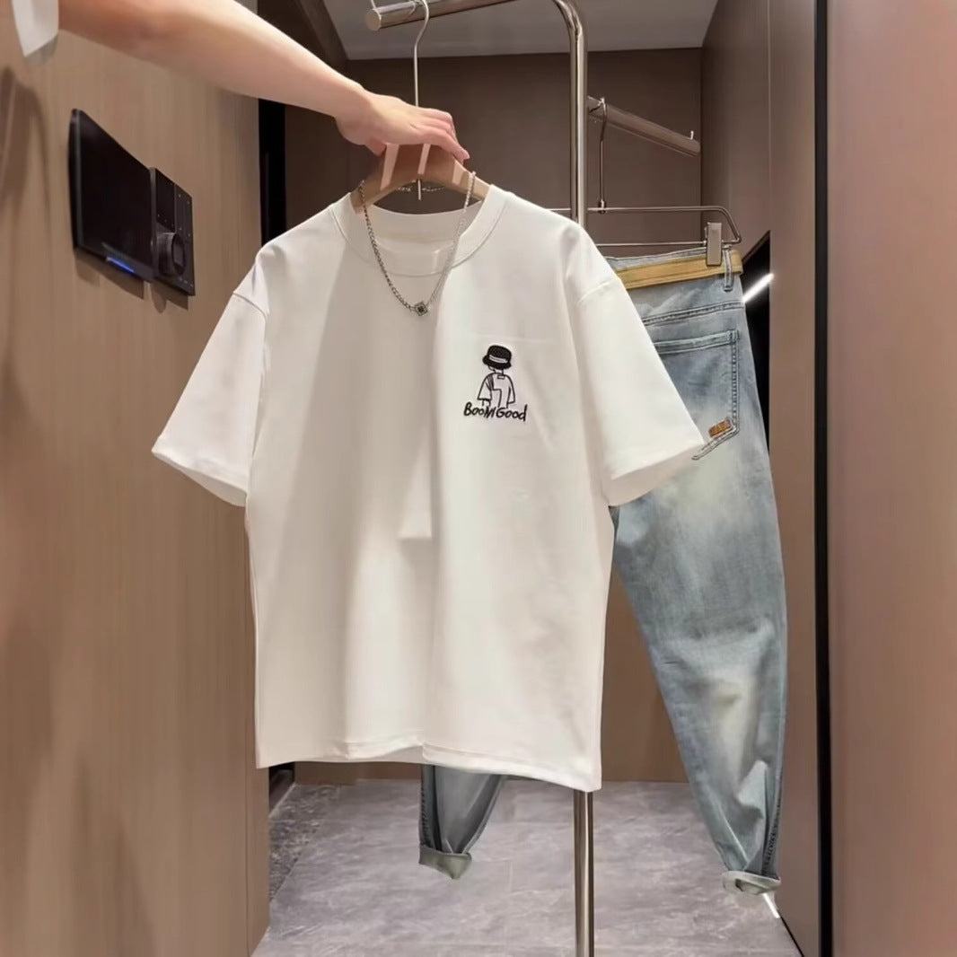 White t-shirt with a graphic design on a hanger, with jeans in the background.