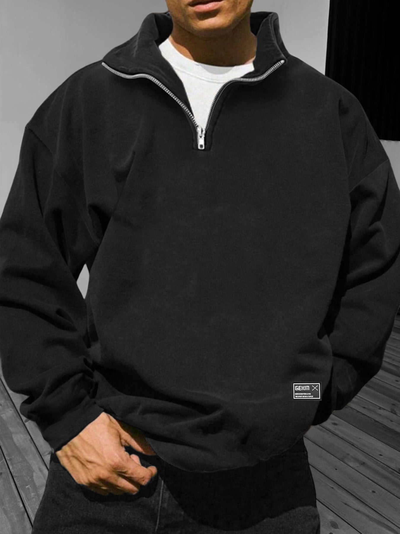 Person wearing a black quarter-zip sweatshirt with a visible brand logo.