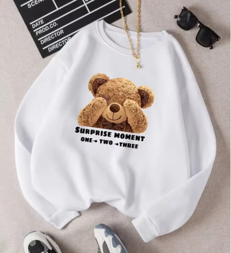 White sweatshirt with a teddy bear graphic and text on a neutral background