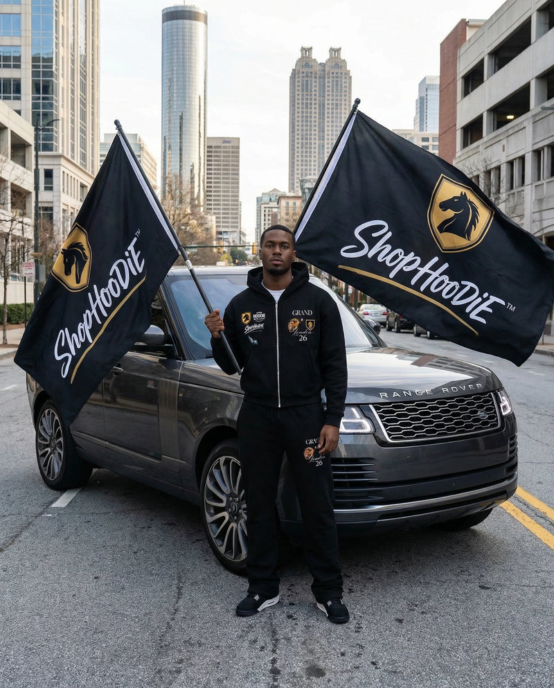 Person holding ShopHoodie™ flags in front of a Range Rover with cityscape background