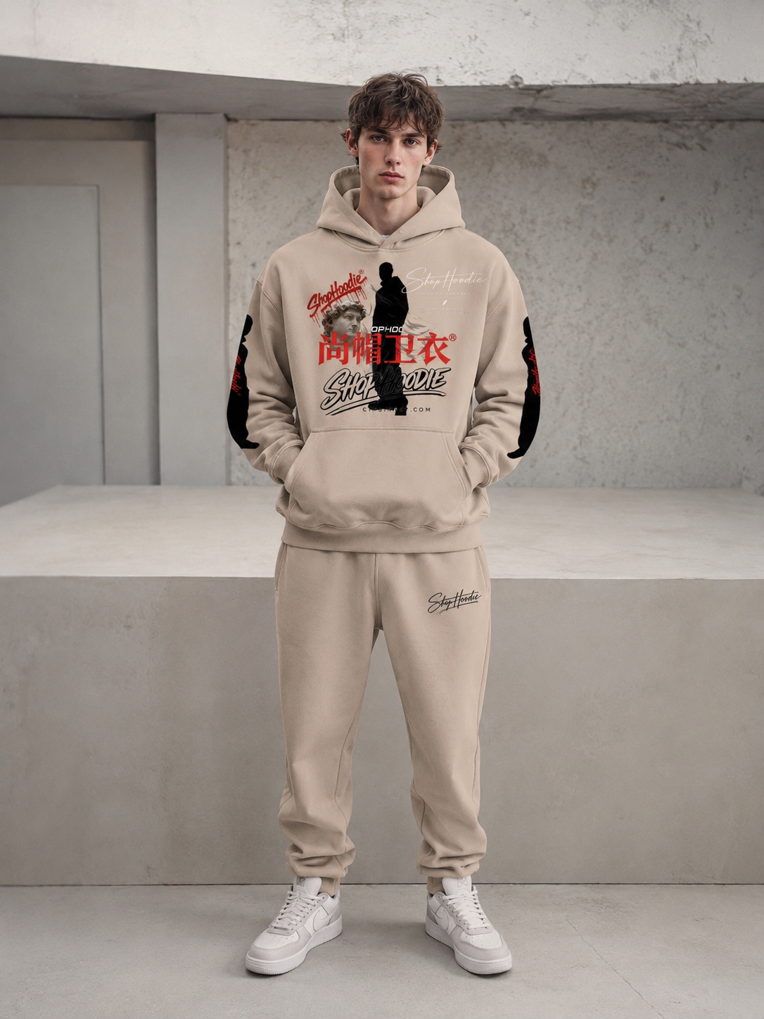 Person wearing a beige hoodie and pants with graphic designs in an indoor setting
