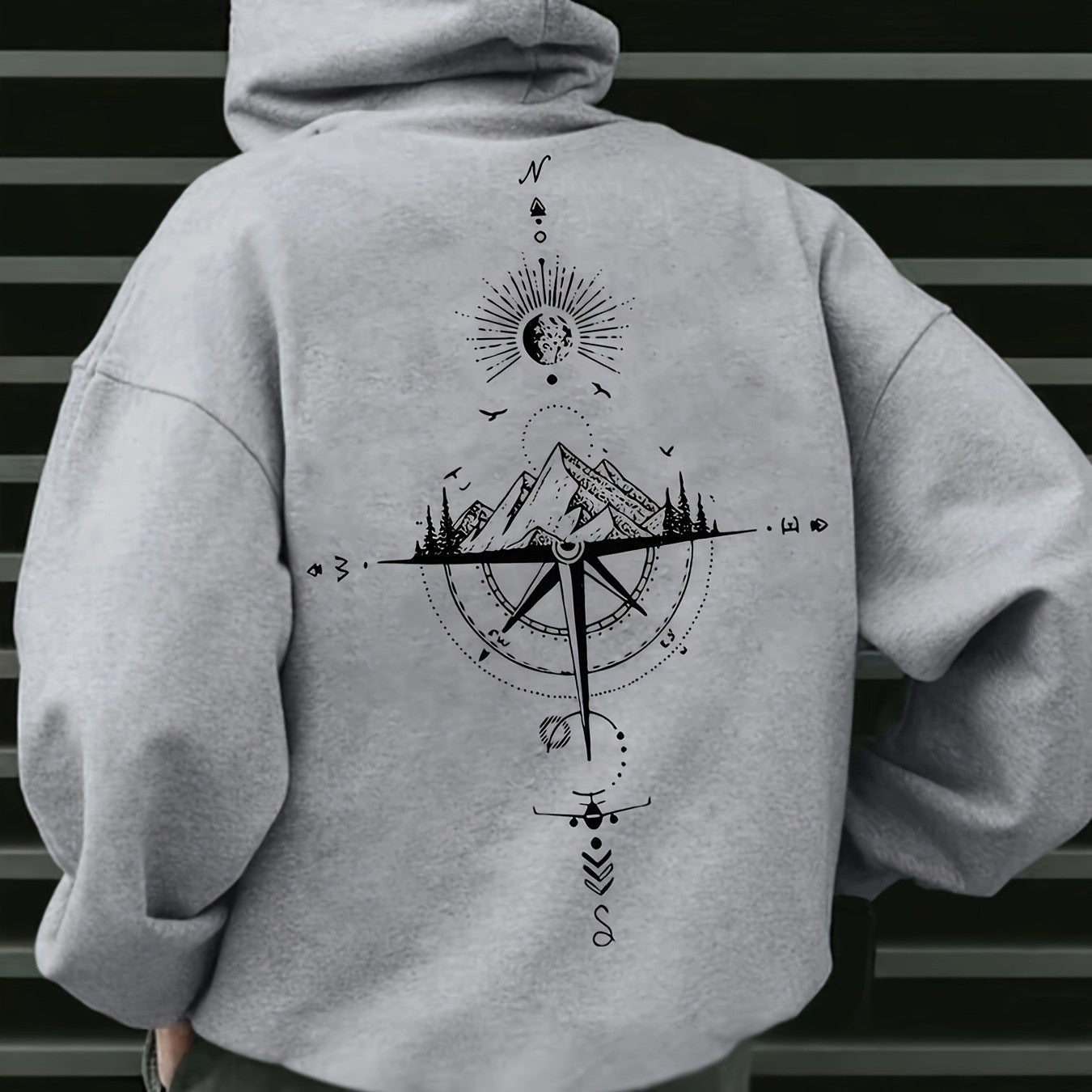 Gray hoodie with a mountain and compass design on the back against a striped background