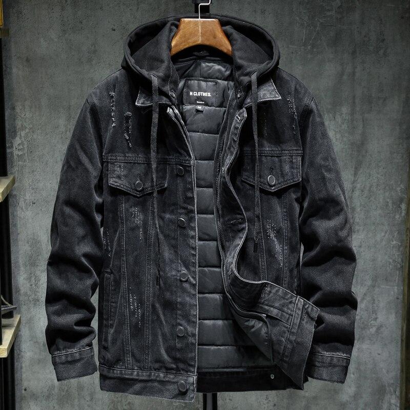 Black denim jacket with quilted lining on a wooden hanger against a gray textured wall.