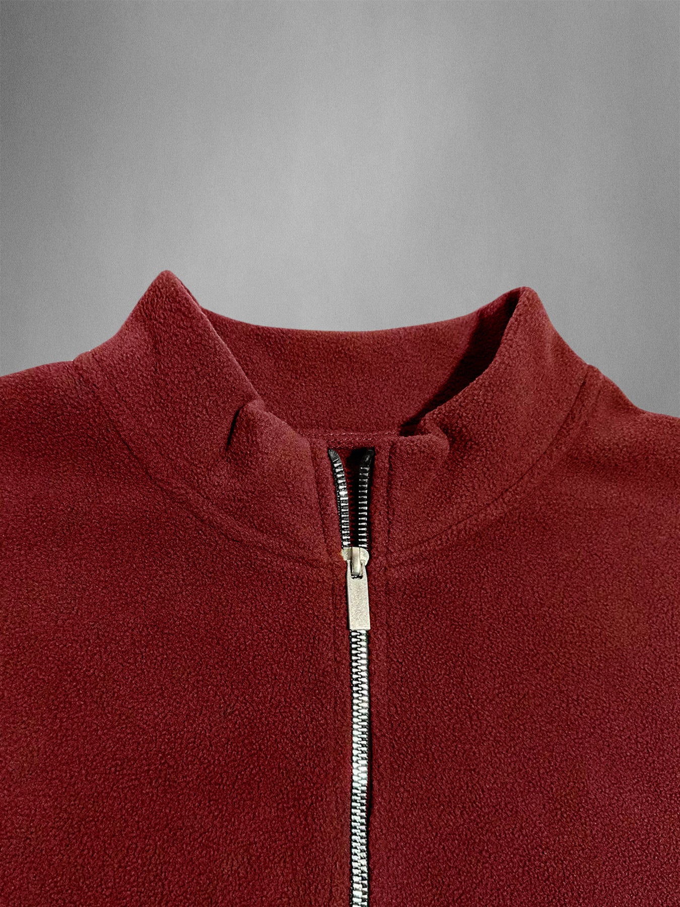 Close-up of a red fleece jacket with a zipper on a gray background