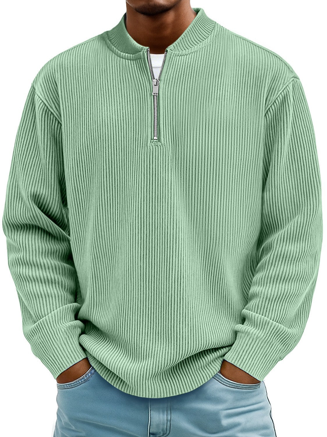 Person wearing a light green ribbed sweater with a zipper on a white background