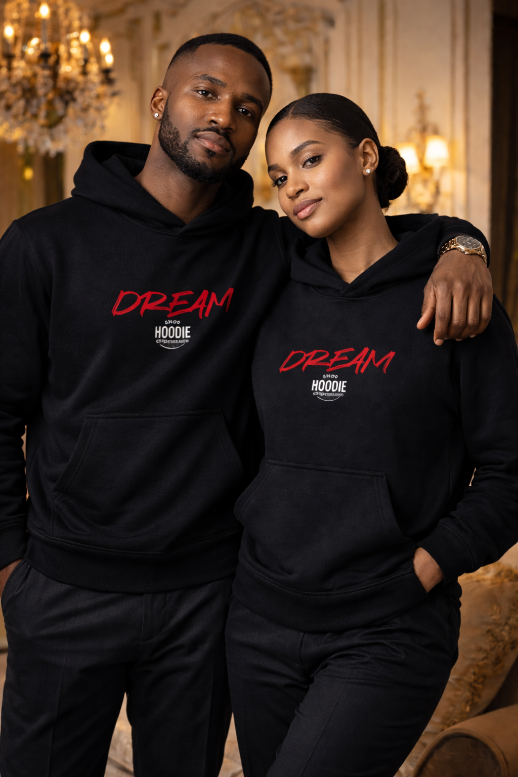 Two people wearing black hoodies with 'Dream' printed on them, standing close together in a decorated room.