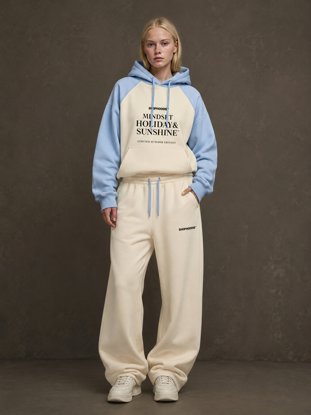 Person wearing a two-tone shophoodie brand hoodie and beige pants against a dark background