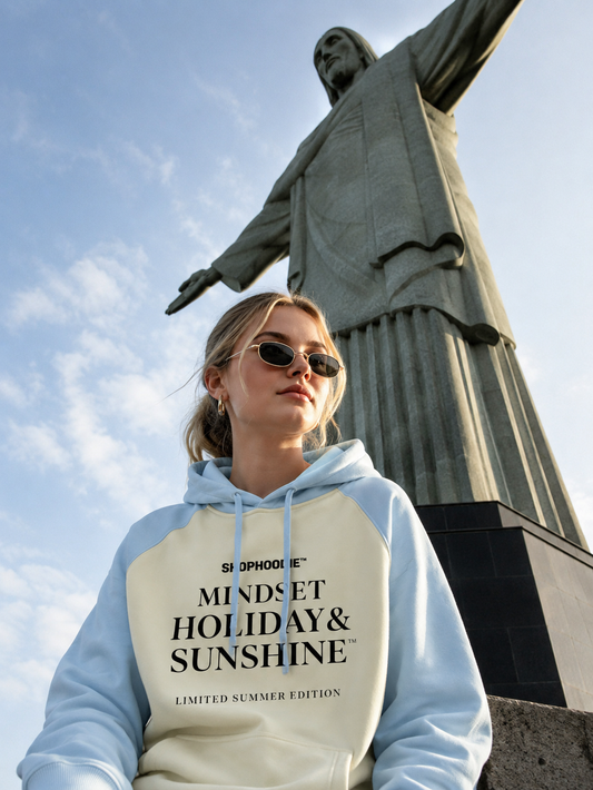 Person wearing a hoodie with text in front of a statue against a blue sky