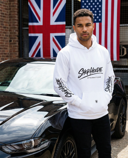 Man wearing a white hoodie with branding in front of a car and flags.