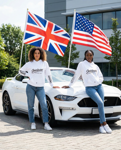 Two people standing in front of a white car holding British and American flags.