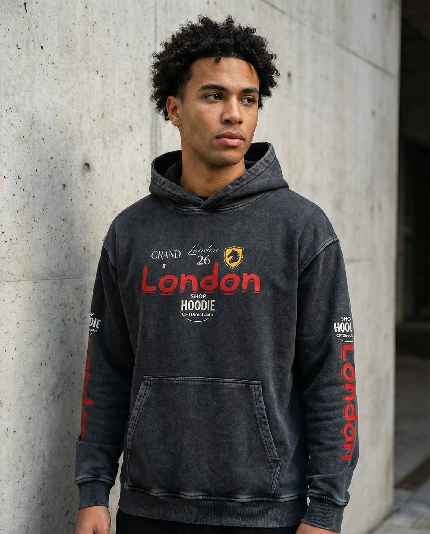 Person wearing a black hoodie with 'London' and 'Grand Hoodie' text, standing against a concrete wall.