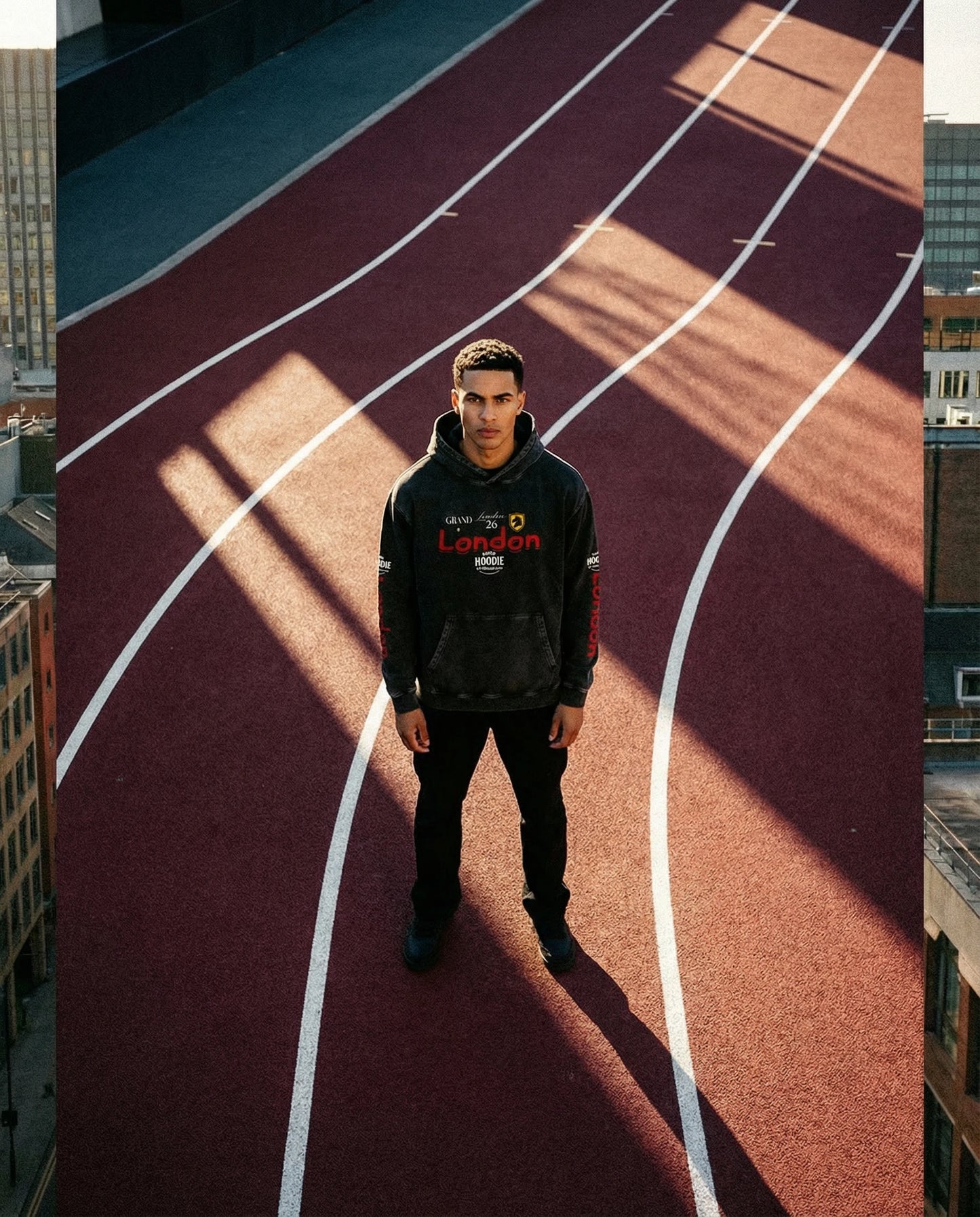 Person wearing a black hoodie with visible branding on a running track