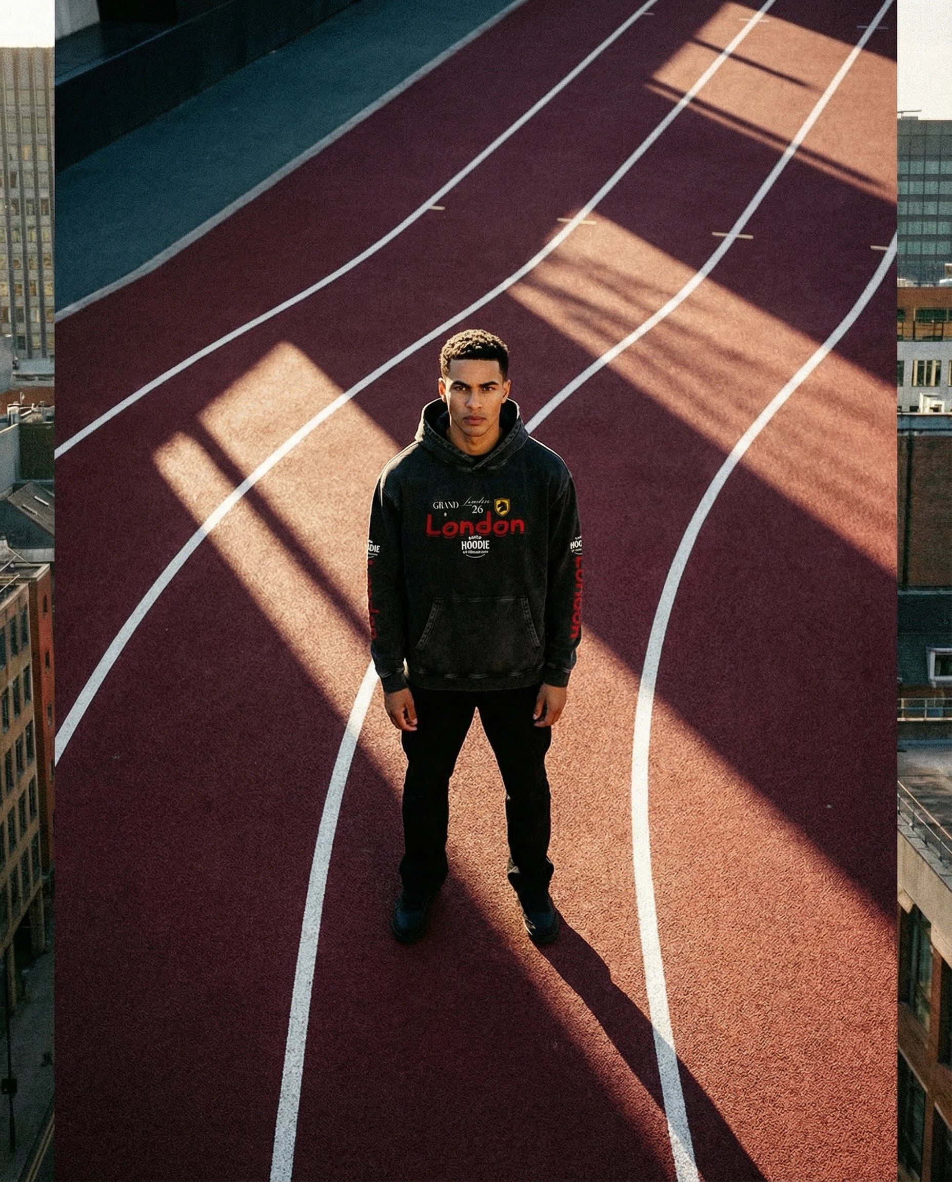 Person wearing a black hoodie with visible branding on a running track