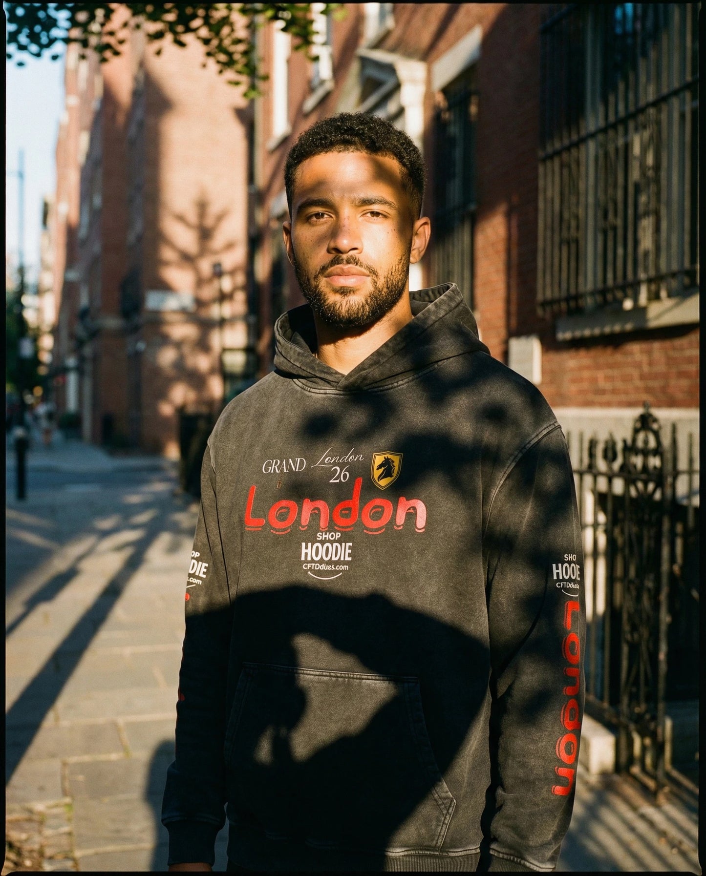 Man wearing a hoodie with text standing on a street