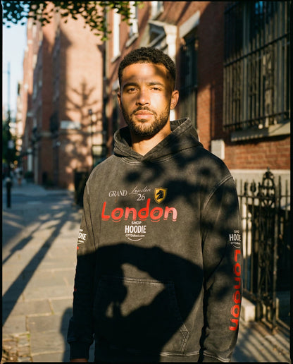 Man wearing a black hoodie with 'London' text standing on a street.