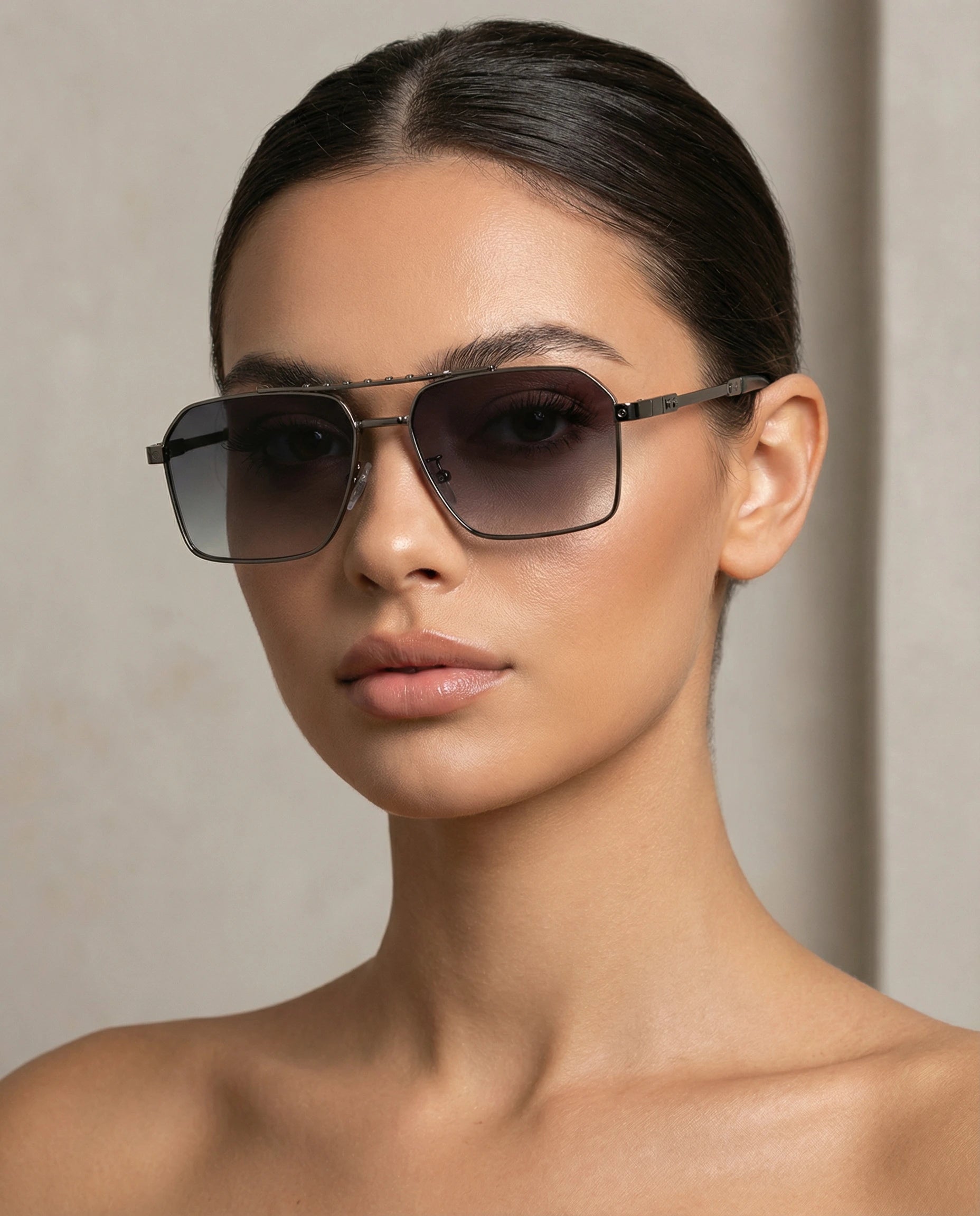 Woman wearing dark sunglasses against a neutral background