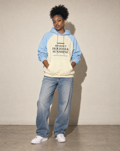 Female model wearing the SHOPHOODIE® Mindset Holiday & Sunshine Raglan Hoodie in Mild Apricot with Sky Blue – full-length studio shot