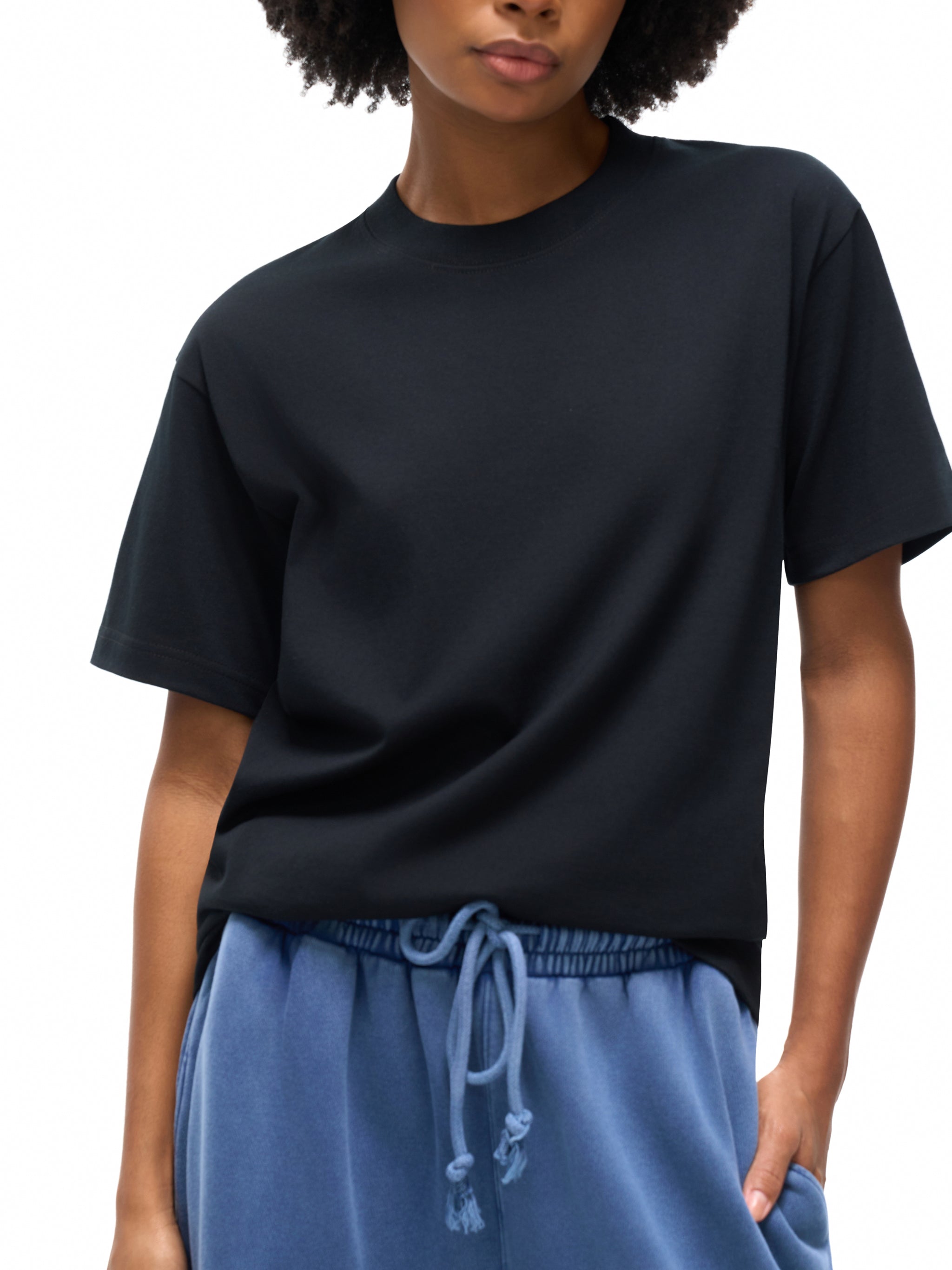 Person wearing a black t-shirt and blue pants on a white background