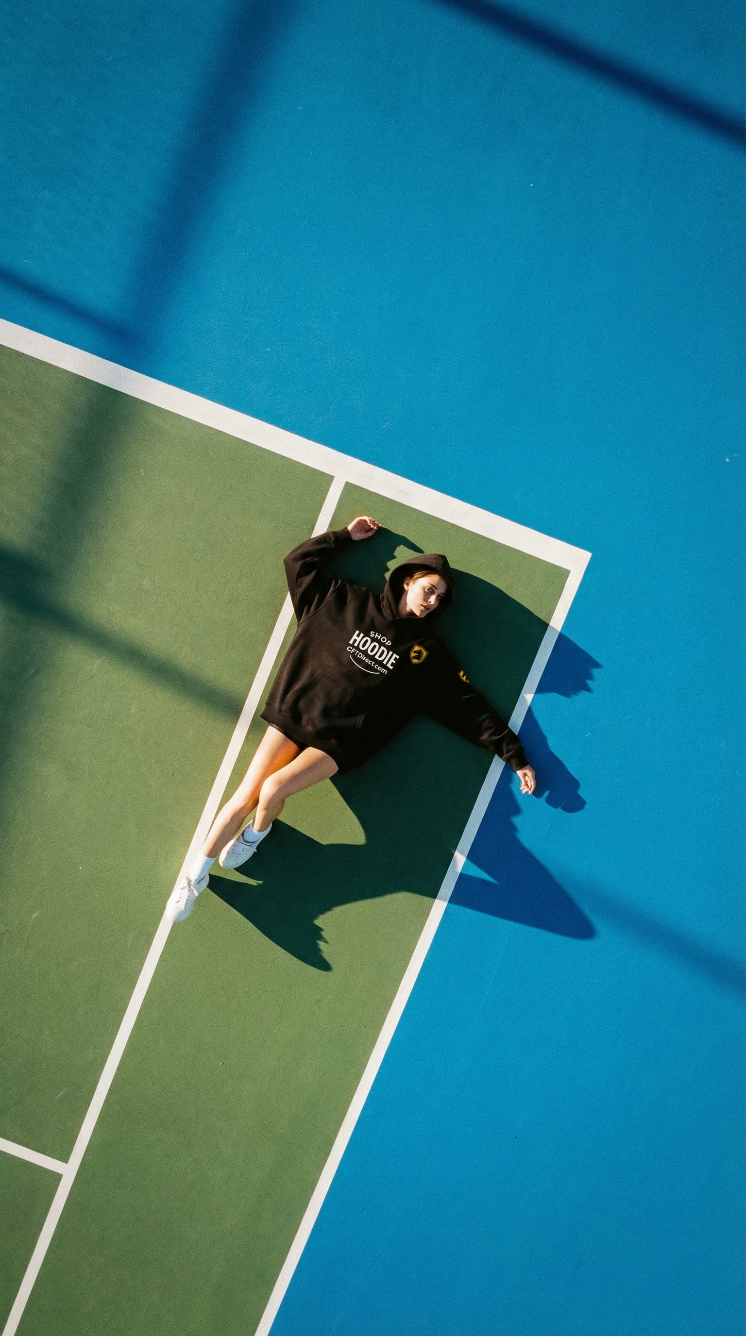 Person lying on a tennis court with a blue and green surface