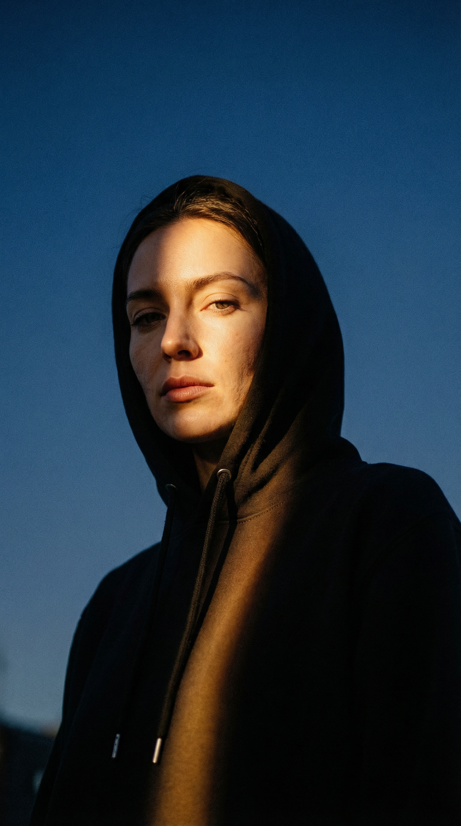 Person wearing a dark hoodie against a blue sky cftdirect.com